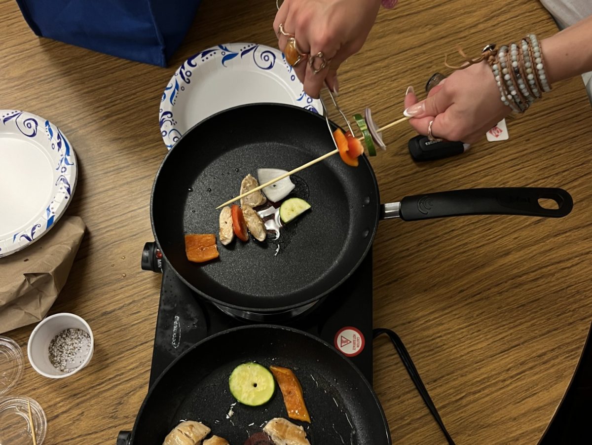 Cooking demonstration of vegetable kabab over a black pan on a burner.