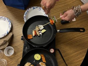 Cooking demonstration of vegetable kabab over a black pan on a burner.