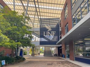 A brick and metal building, with a large navy blue banner containing the UNF logo hanging from the front.