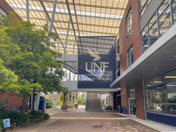 A brick and metal building, with a large navy blue banner containing the UNF logo hanging from the front.