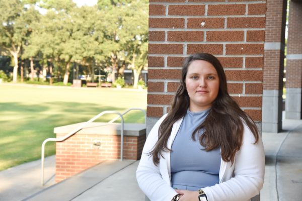 Caroline Nickas stands in front of the UNF Green by a brick pillar