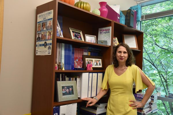 Madalina Tanase is smiling wearing a yellow dress, standing in front of a bookcase