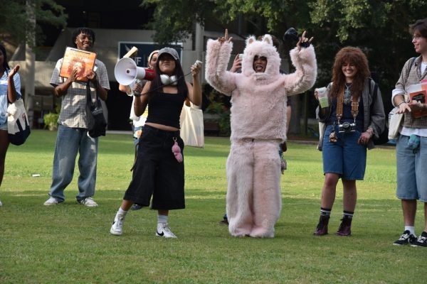 The contestant dressed as a fluffy, light pink Labubu holds arms up in the air in triumph