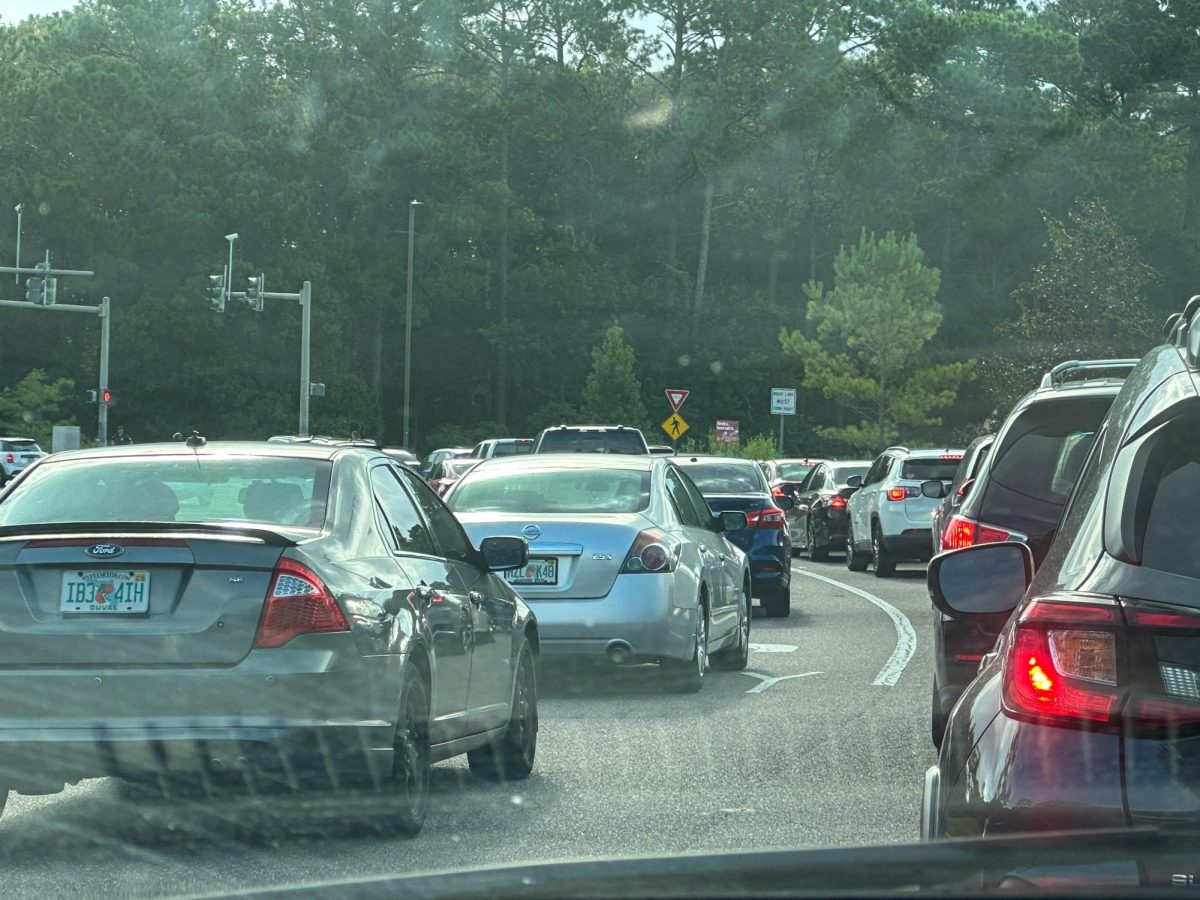 Multiple grey and black cars sit in traffic.