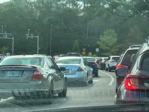 Multiple grey and black cars sit in traffic.