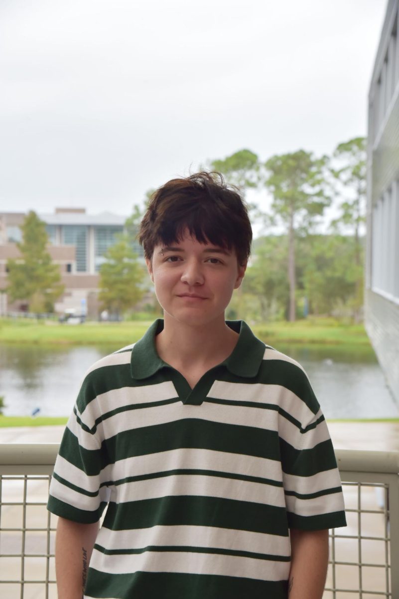 RJ is smiling with short black hair, wearing a green and white stripe polo shirt.
