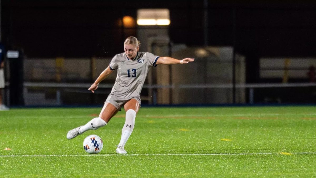 A soccer player wearing grey is pictured while she is about to kick the ball.