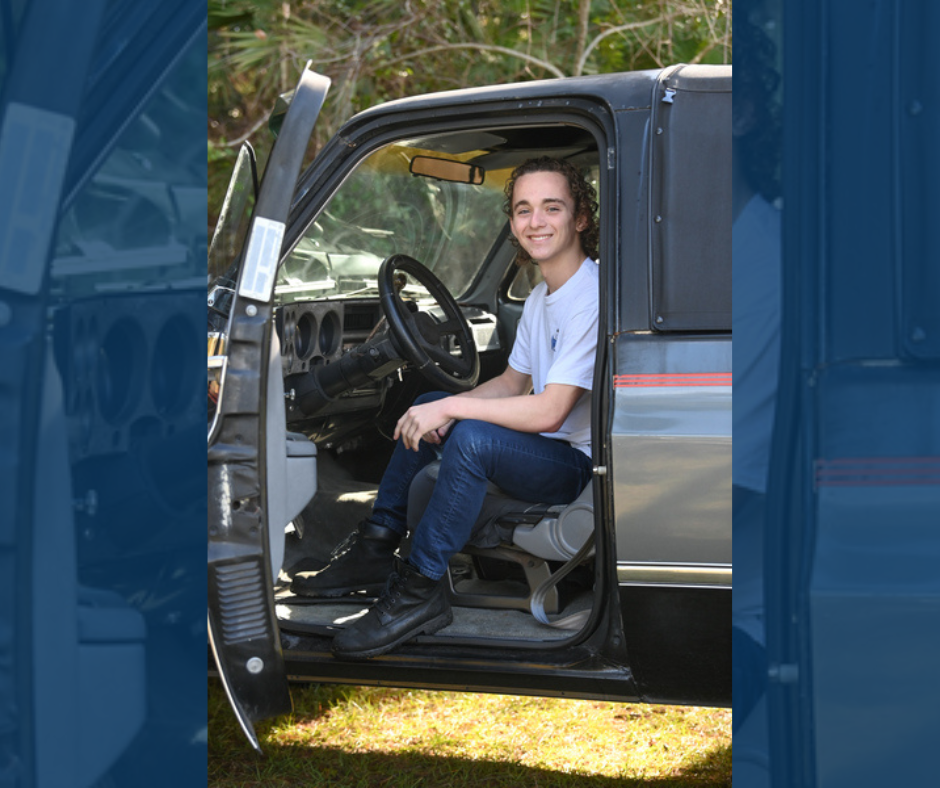 Hunter Ford smiles, sitting in a truck in the driver's seat.