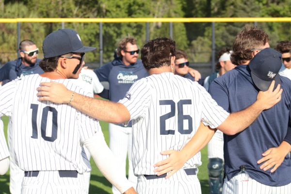 UNF baseball team stand in circle with arms around eachother