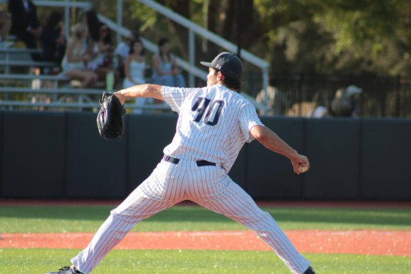 Pitcher in white steps forward to throw the baseball. 