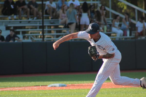Pitcher in white throwing baseball.