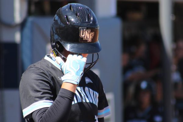 Softball player wiping her eye through helmet.