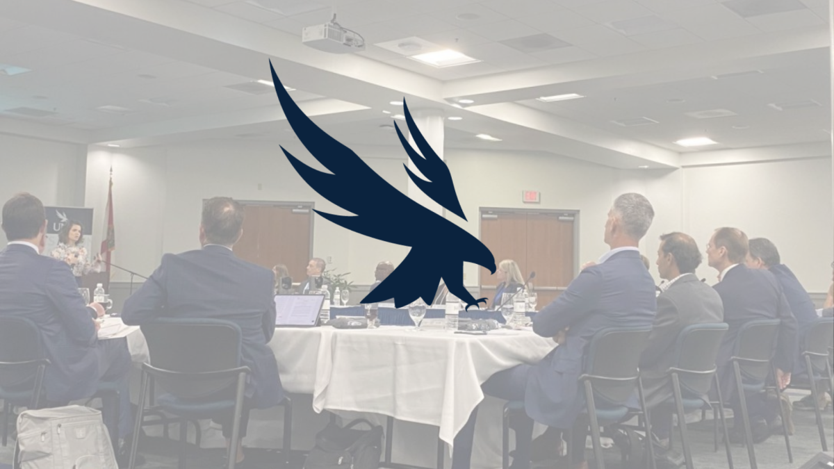 Photo of UNF's board of trustees sitting around a table. UNF's Osprey logo is overlaid on the image.