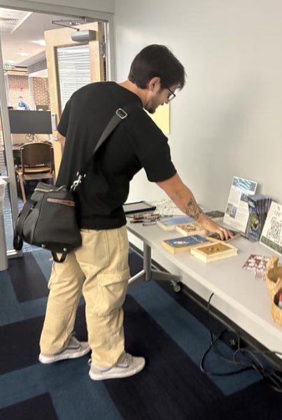 Man leans over table to write on poster.