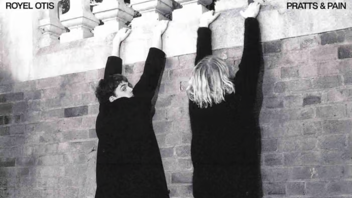 Black and white photo of two men hanging from a brick wall.