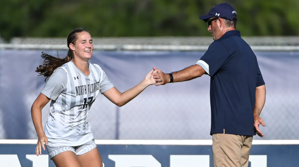 UNF women's head soccer coach giving high five to student athlete.