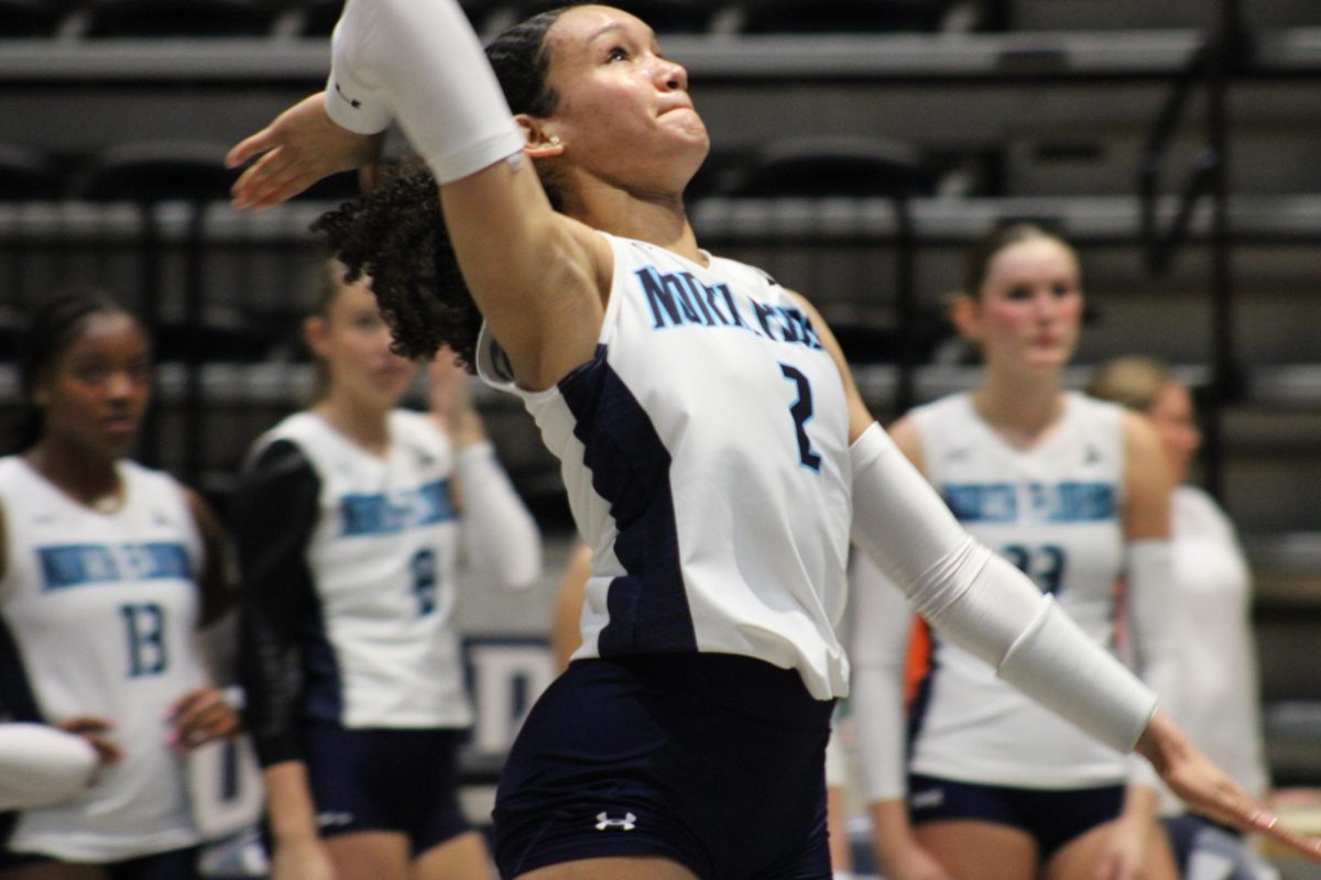 Volleyball player jumps up to hit ball.