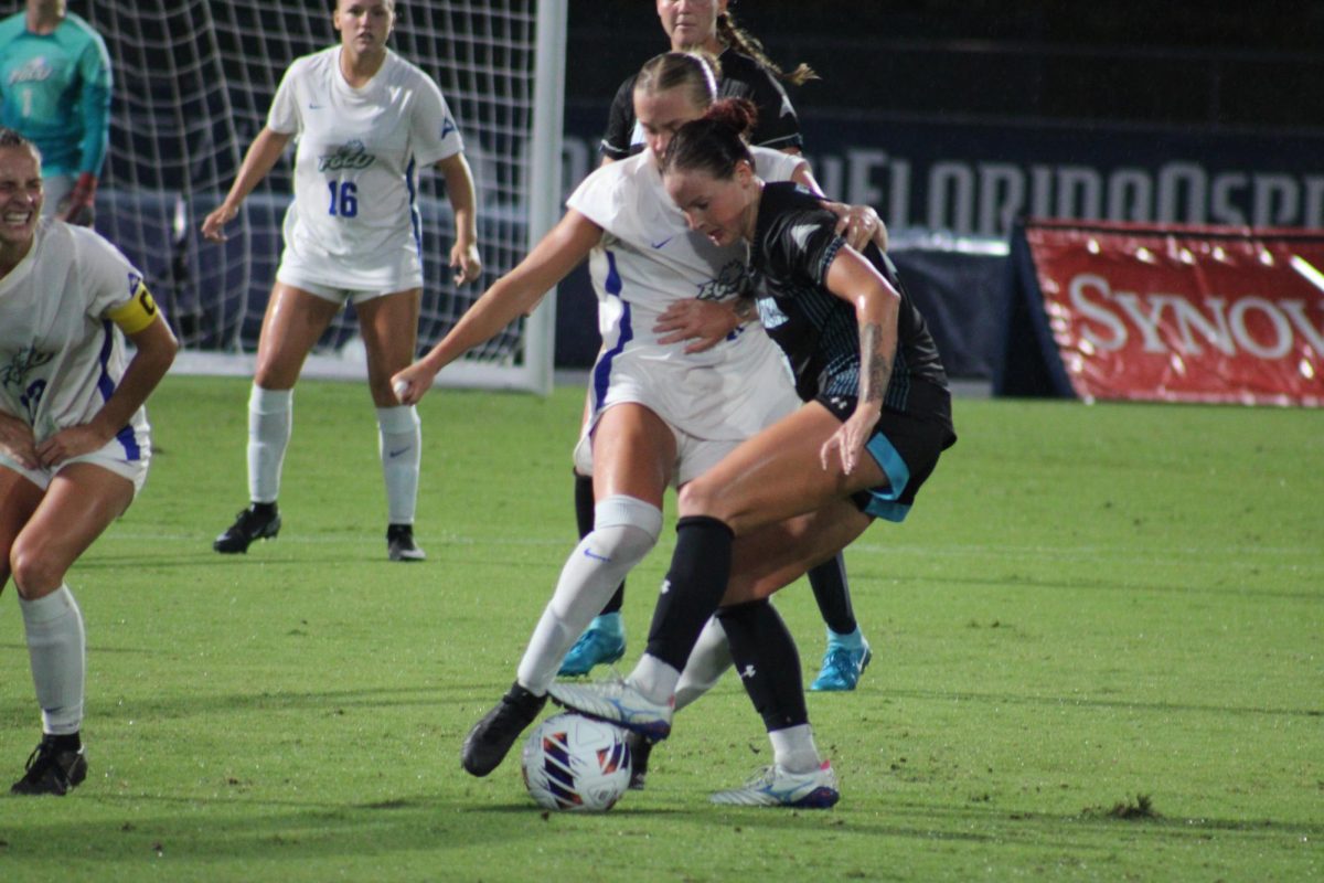 Image shows two women soccer players in active pursuit of a soccer ball, their feet moments from clashing