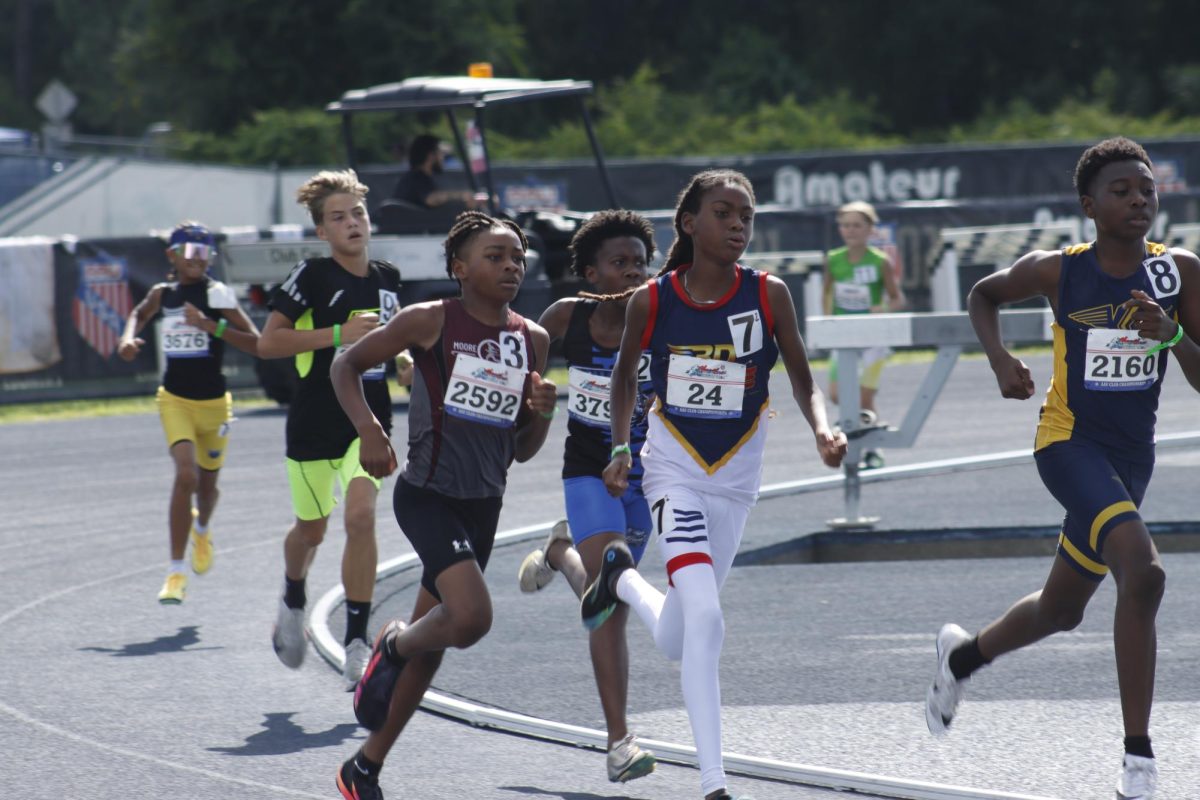 Young athletes are running on a track under a bright sun