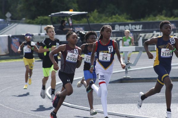 Young athletes are running on a track under a bright sun