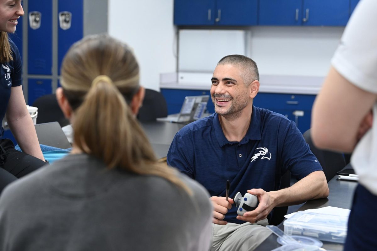 Image shows smiling man with buzzed head and beard wearing a UNF Osprey polo